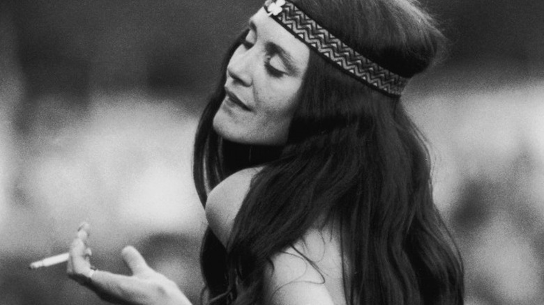 Black and white photo of a young hippie girl smoking eyes closed