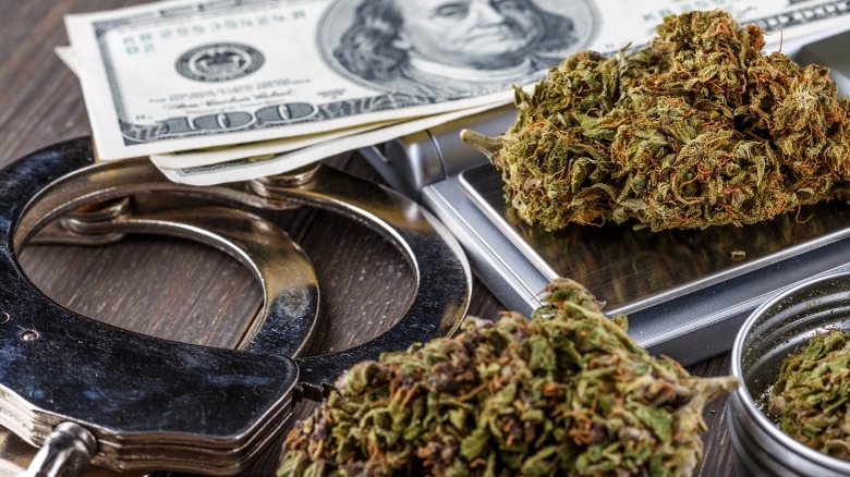 Close-up of cash, handcuffs, and marijuana buds wooden table