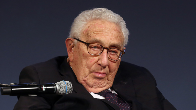 Henry Kissinger speaking into microphone