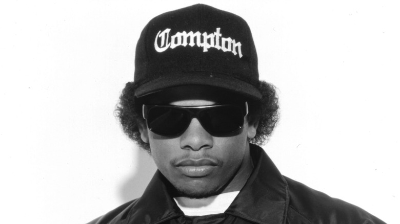 Eazy-E in a baseball cap and sunglasses posing for a publicity photo in 1990