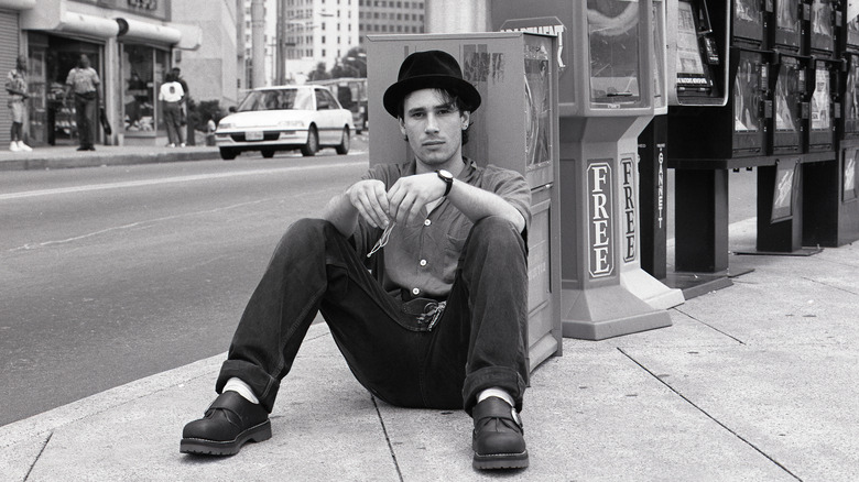 Jeff Buckley sitting on the ground in a city