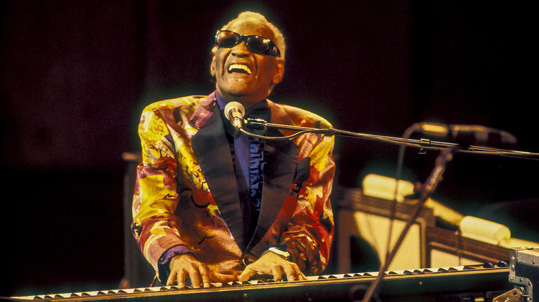 Ray Charles playing piano behind a microphone onstage