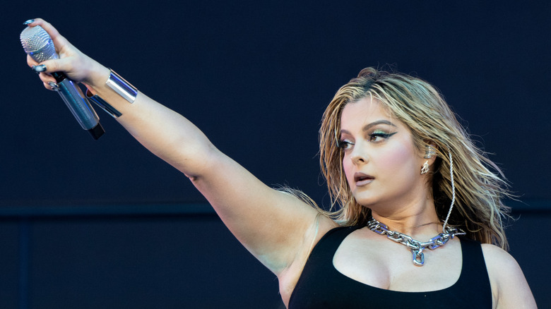 Bebe Rexha holding out a microphone on stage