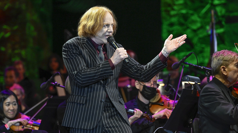 Danny Elfman sings on stage in front of an orchestra