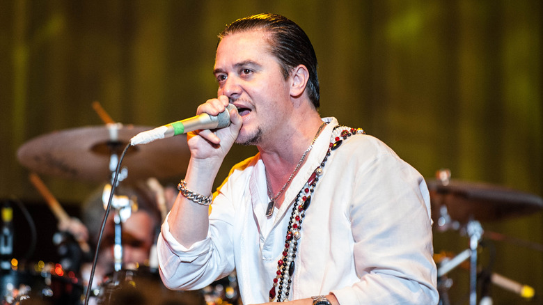 Mike Patton speaks into a microphone on stage