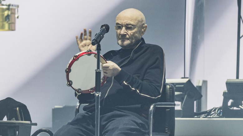 Phil Collins plays tambourine on stage