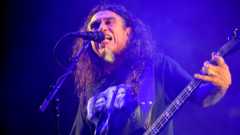 Tom Araya singing into a microphone and playing bass