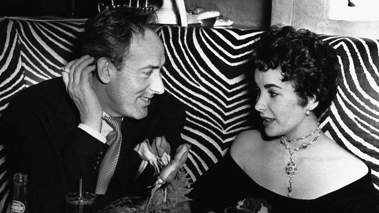 Michael Wilding and Elizabeth Taylor talking at a table