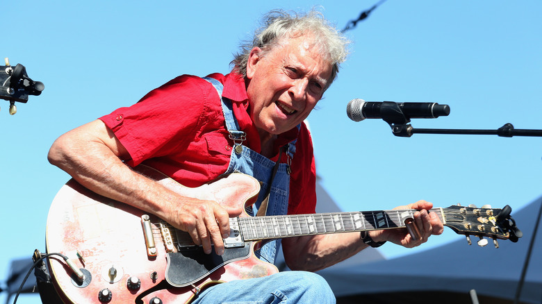 Elvin Bishop playing guitar in front of a microphone