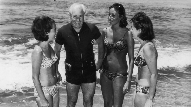 Harold Holt surrounded by three women on the beach