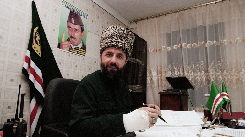 Zelimkhan Yandarbiyev in hat at desk with pen