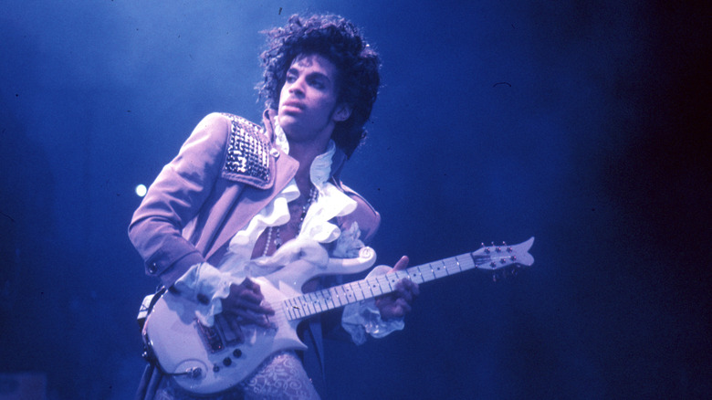 Prince wielding a guitar at concert