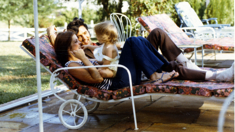 Priscilla and Elvis Presley playing with their daughter outside