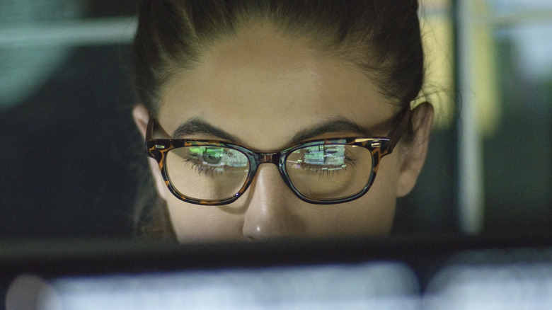 bespectacled woman looking at computer screen