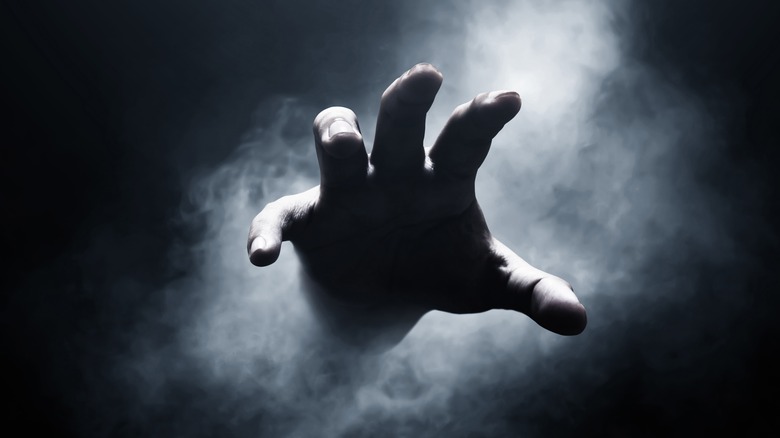 dead person's hand emerging from smoke