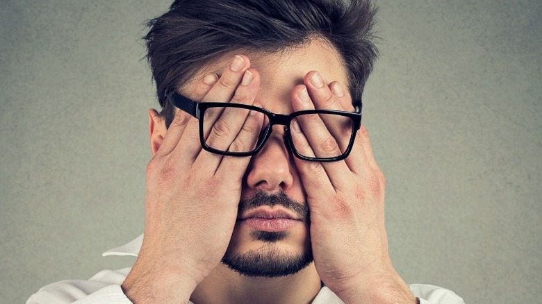 man with glasses covering his eyes