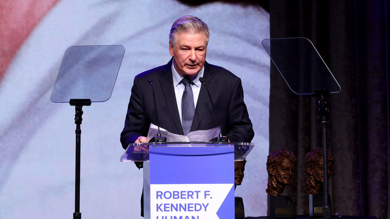 Alec Baldwin in suit at mike speaking at RFK Human Rights conference