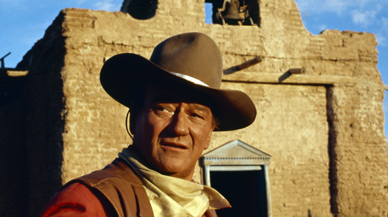 John Wayne in cowboy hat in front of brick building