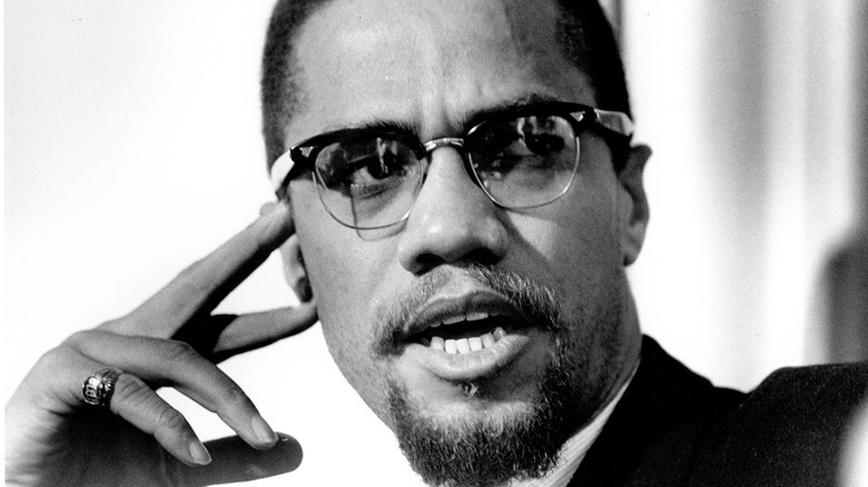 Malcolm X with fingers touching face