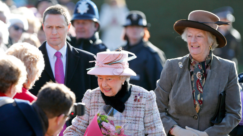 Queen Elizabeth II receiving flowers with bodyguard