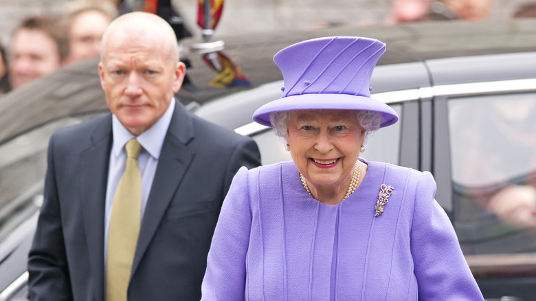 Queen Elizabeth II purple hat with bodyguard