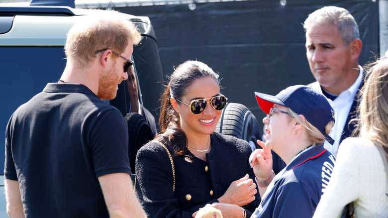 Prince Harry and Meghan Markle greet people with bodyguard