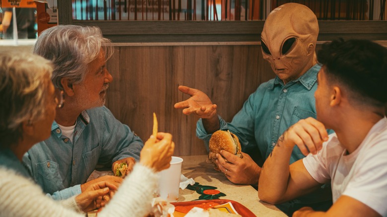 Alien eating hamburger with family