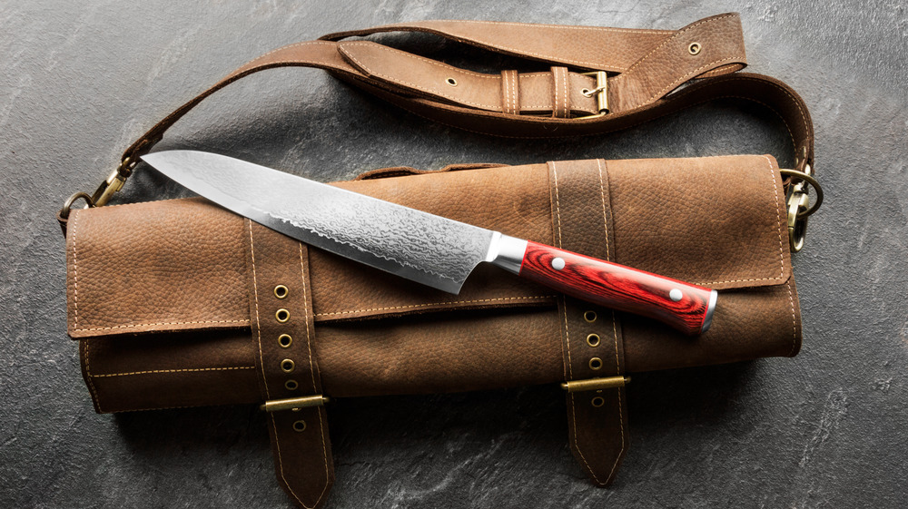 damascus steel knife on top of leather bag