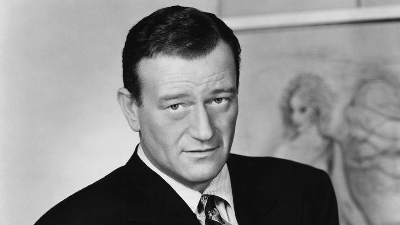 John Wayne suit posing painting in background