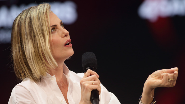 Charlize Theron gesturing while holding a microphone
