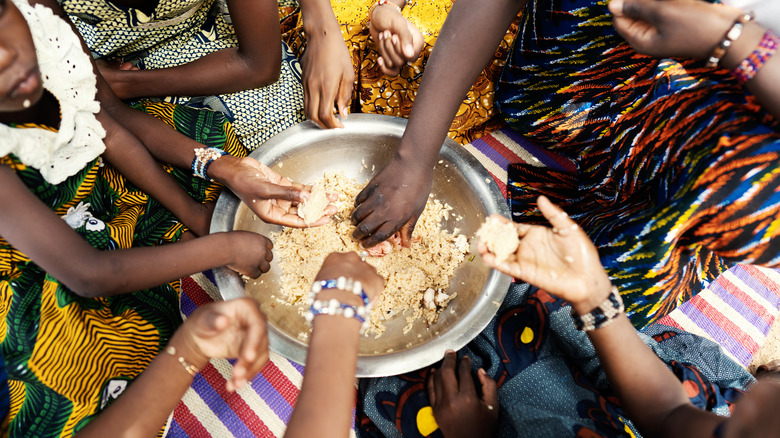 African kids taking food from a metal bowl