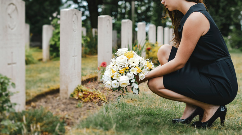 A widow with flowers at a gravesite