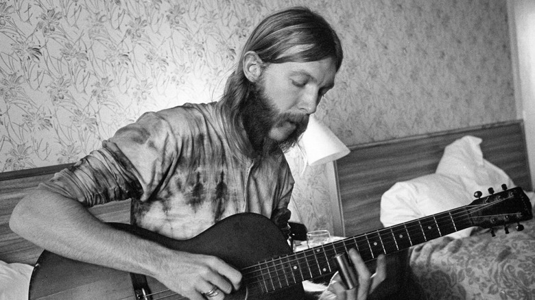 Duane Allman plays guitar on couch