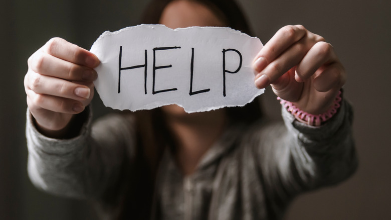 woman holding "help" sign