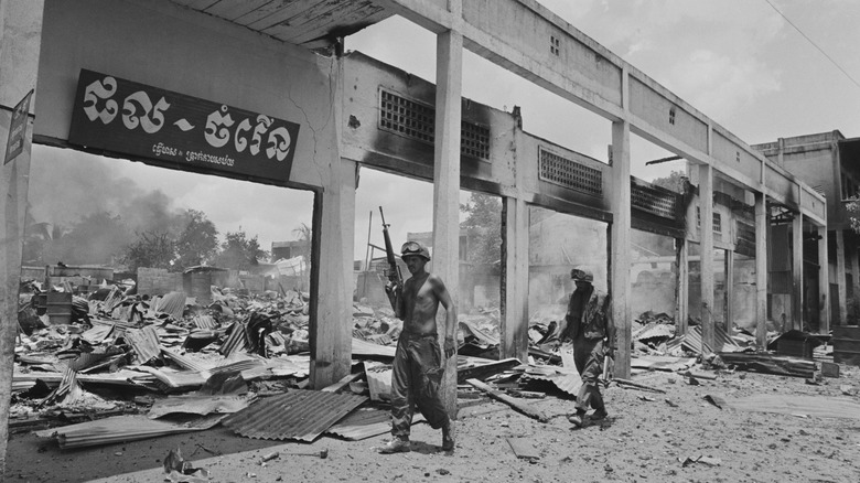 Soldiers walking alongside destroyed buildings