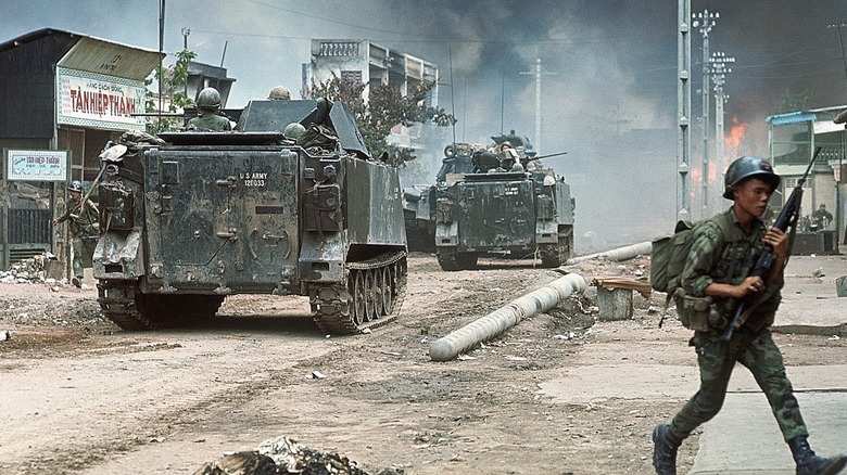 Vietnamese soldier running behind tanks