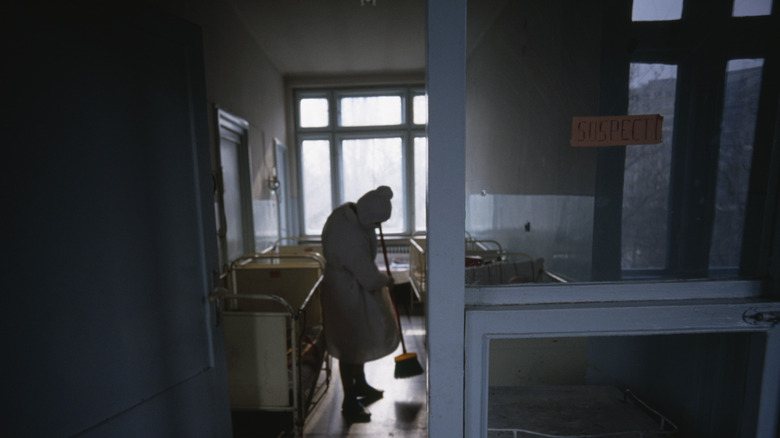Nurse sweeping hospital room floor