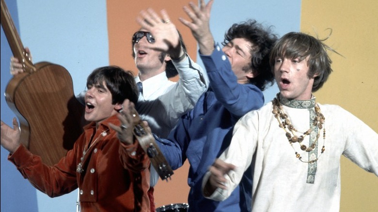 The Monkees singing and holding instruments