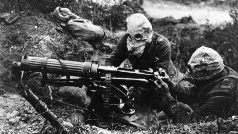 soldiers in trench with machine gun and wearing gas masks