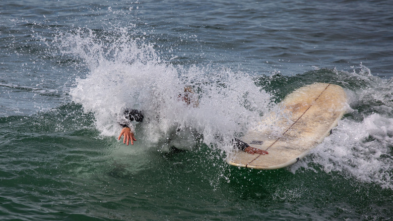surfer grabbing board after wipeout