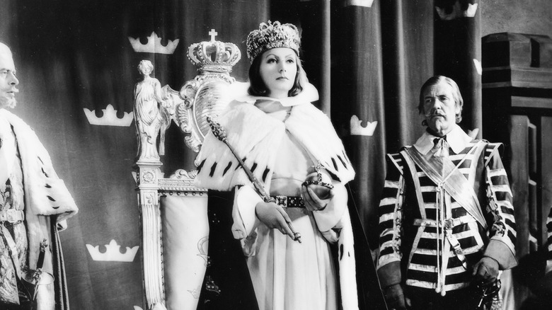 Greta Garbo as Queen Christina wearing a robe and crown with a footman