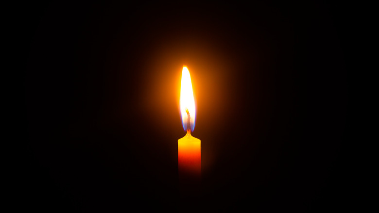 Single candle burning at night