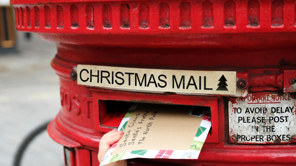 Child is posting a letter for Santa Claus into the Christmas English post