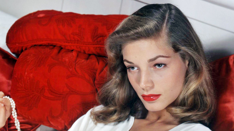Lauren Bacall in white dress on red seat