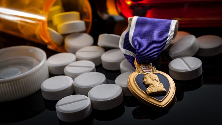A purple heart medal on top of pills spilling out of a prescription bottle