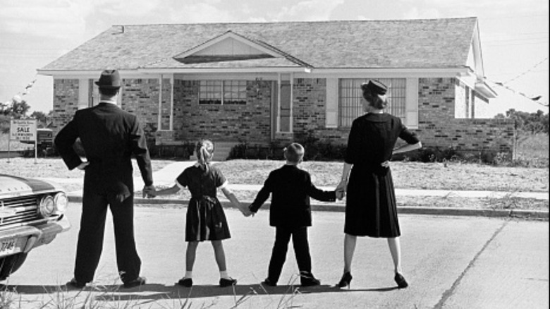 1950s family holding hands looking at house