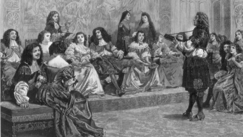 King Charles II sitting on his throne surrounded by courtiers and ladies