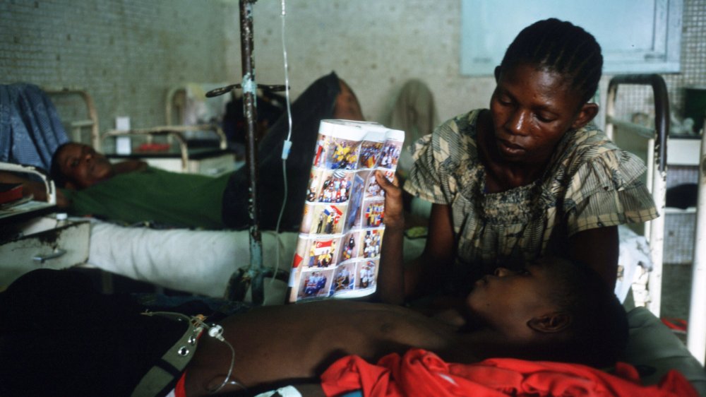 A boy reads a magazine with his mother October 22, 1997 in Kinshasa, Democratic Republic of the Congo.