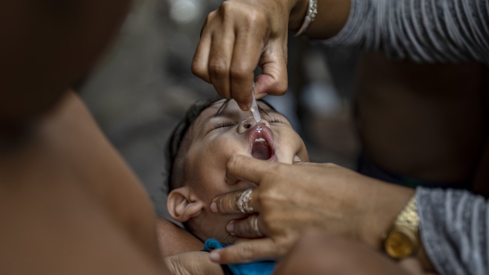 Filipino health worker administers an oral polio vaccine to a child, during a mass vaccination campaign to combat the resurgence of the polio virus,
