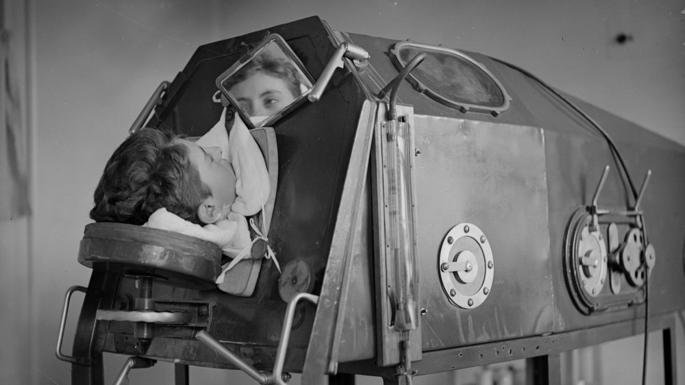 1938: A patient lying in an artificicial respiration machine called an iron lung.